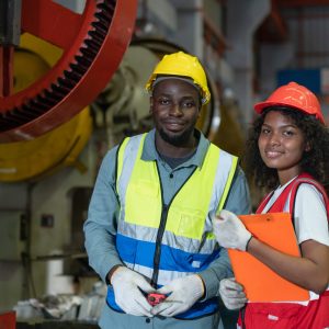 Portrait of African American male and female worker wearing safety vest with helmet smiling look at camera while working in factory