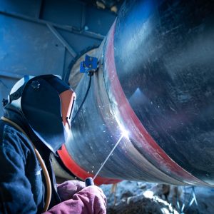 Professional welder welding pipe on a pipeline construction.